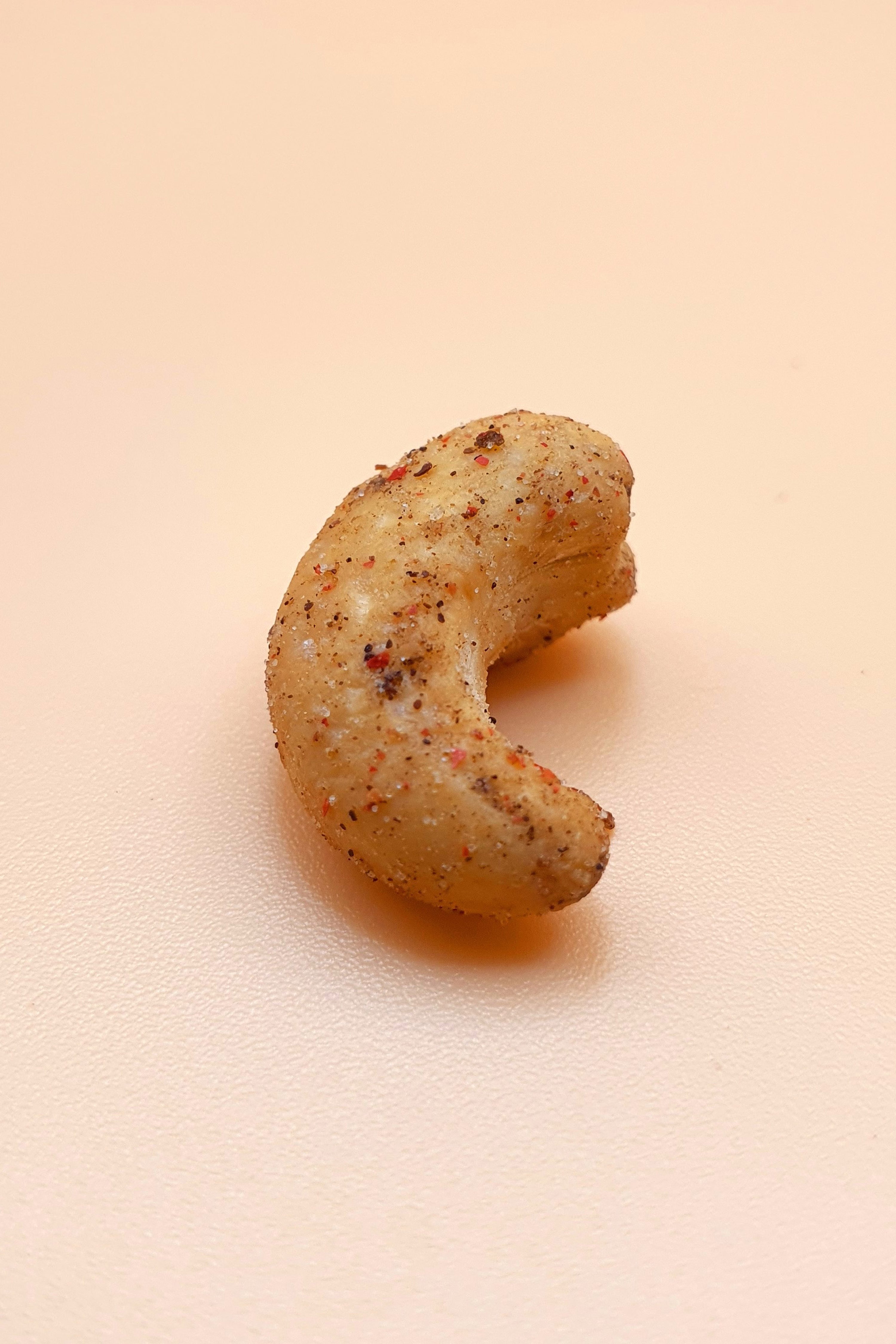 einr gerösteter Cashewkern mit Pfeffer vor neutralem Hintergrund 
