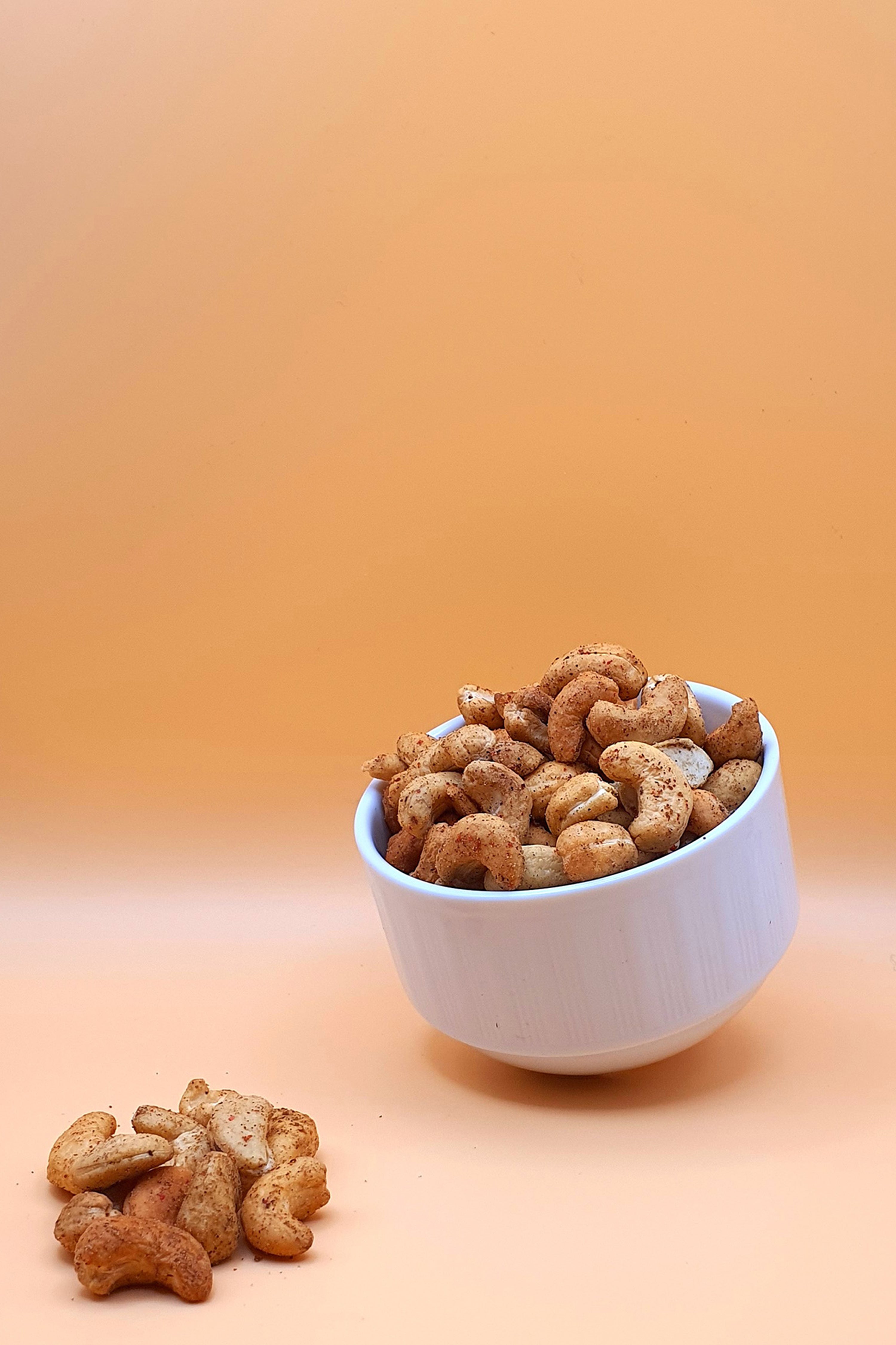 Cashewkerne geröstet mit Pfeffer 1000 g serviert in einer Schale vor neutralem Hintergrund