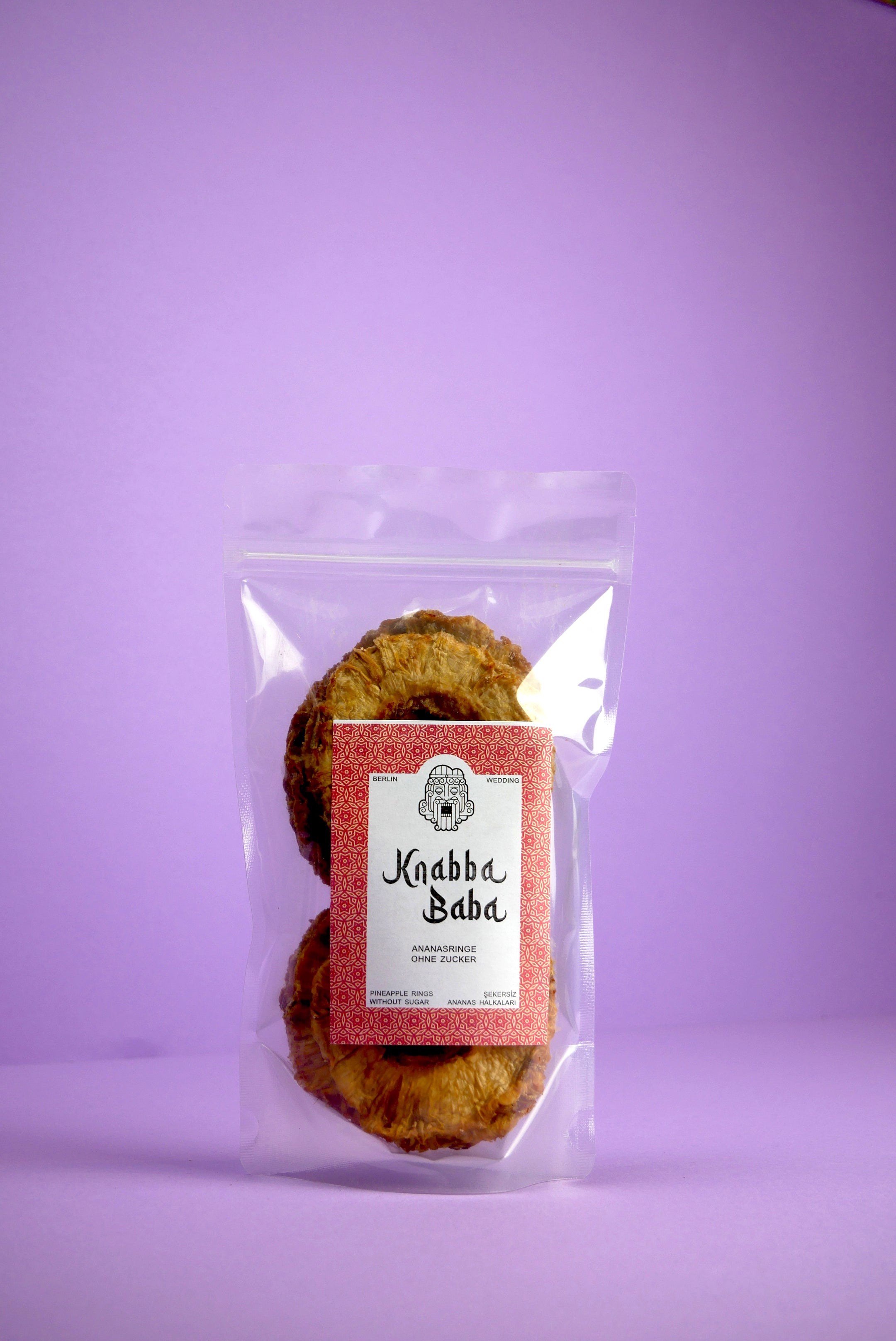 Knabba Baba Packung mit getrockneten Ananasringen 250 g vor lila Hintergrund