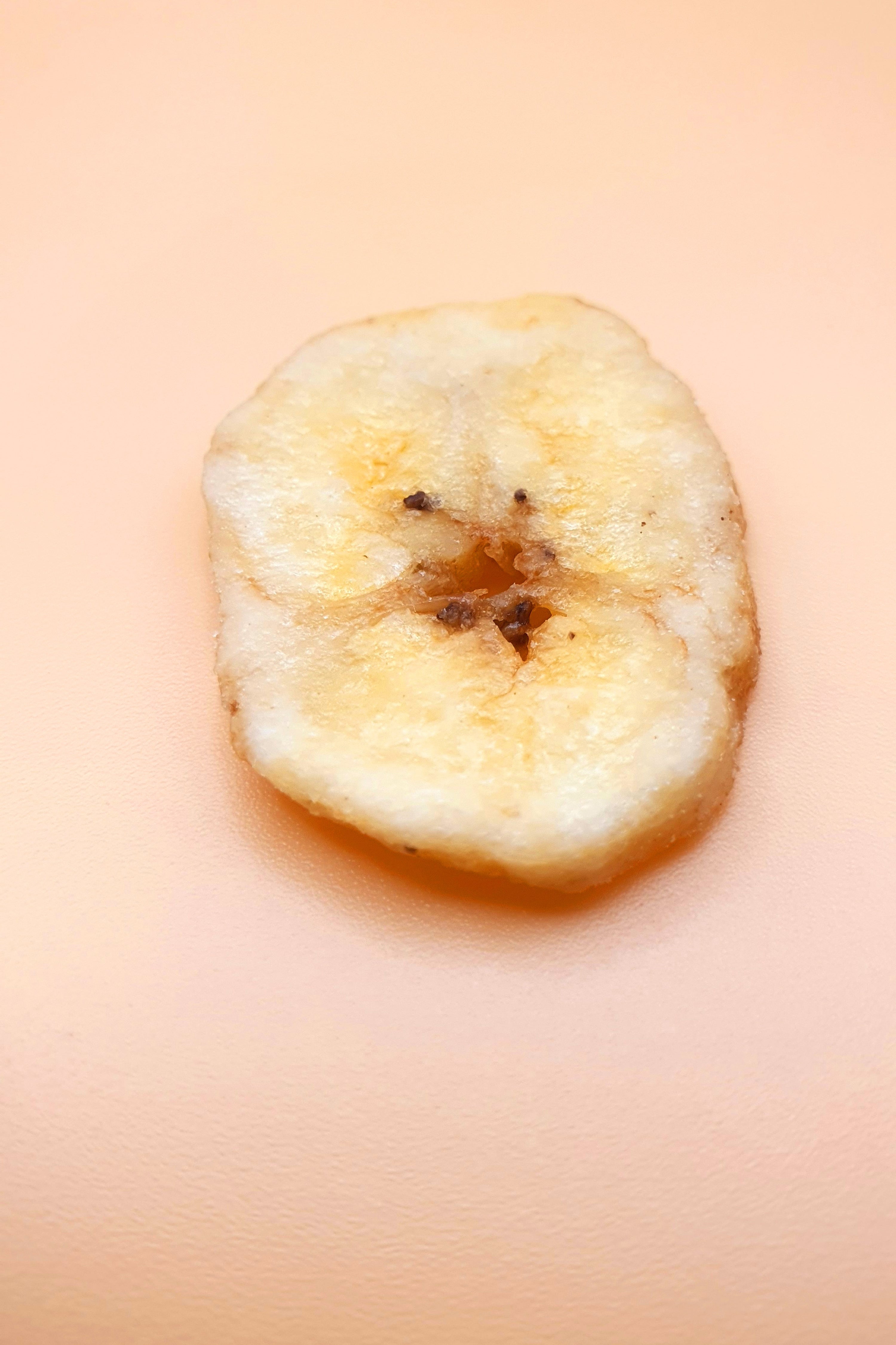 ein getrockneter Bananenchips vor neutralem Hintergrund von Knabba Baba 