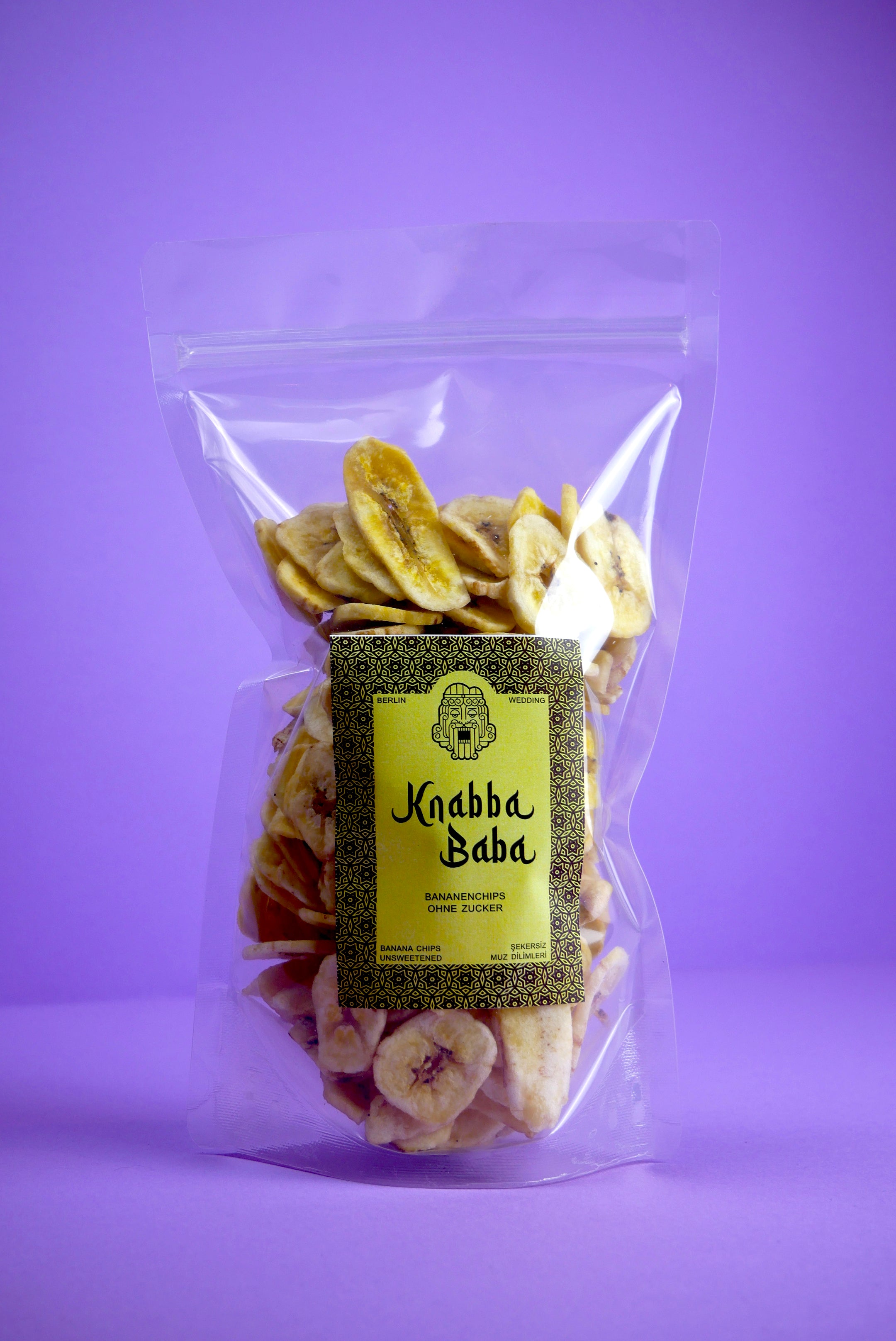 Knabba Baba naturbelassene Bananenchips 500 g im wiederverschließbaren Beutel vor lila Hintergrund