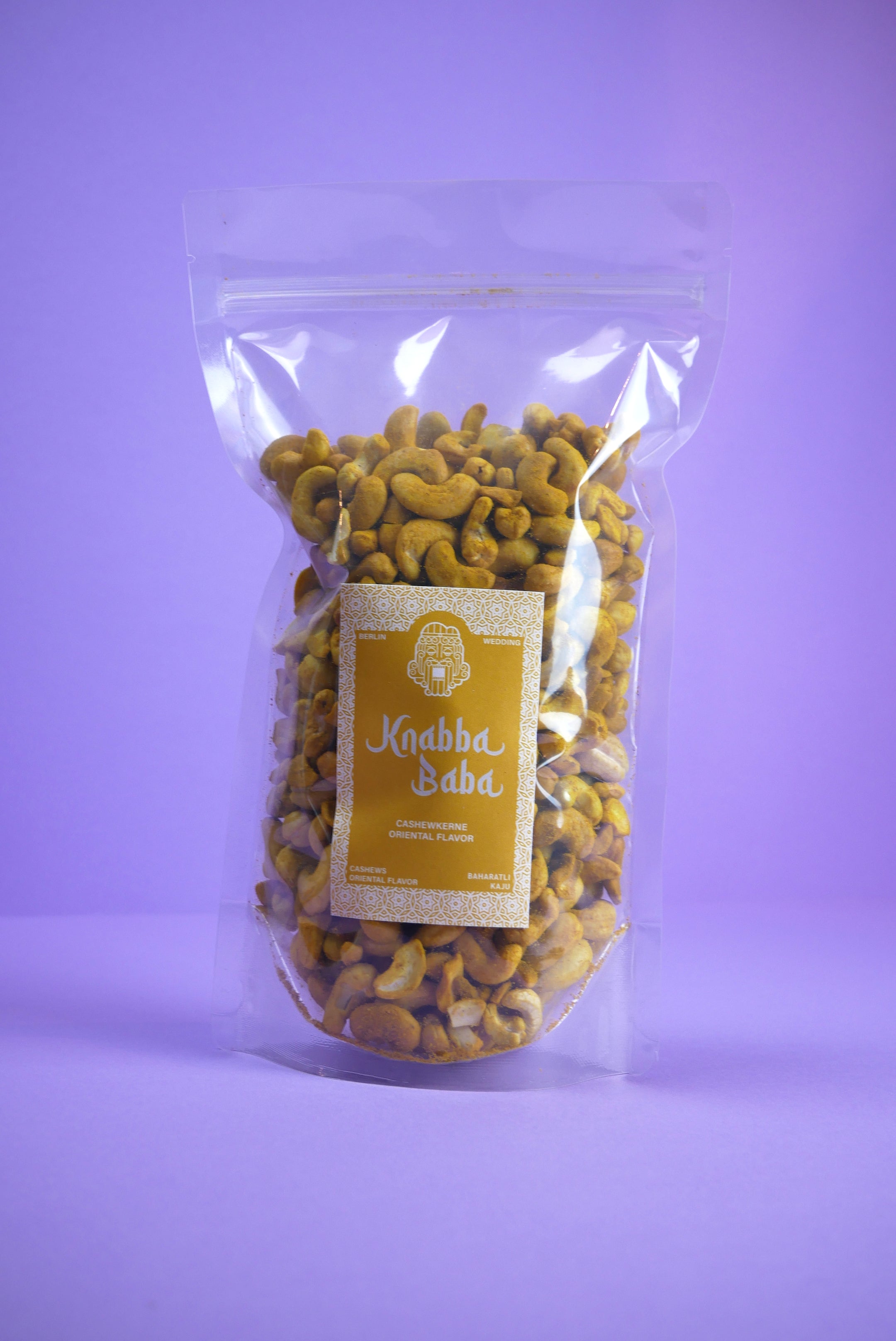 Knabba Baba geröstete Cashewkerne mit Curry 1 kg in transparenter wiederverschließbarer Verpackung vor lila Hintergrund