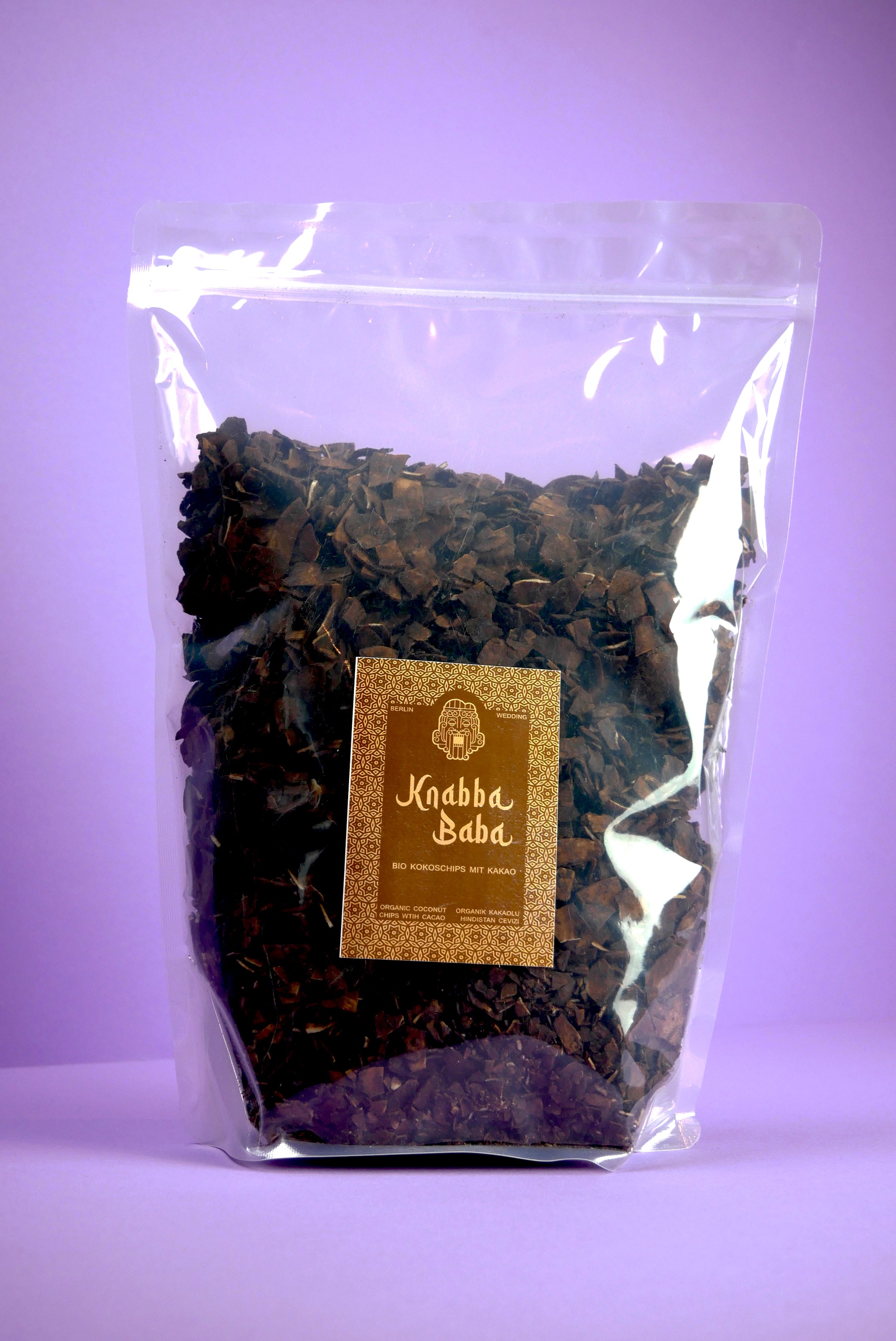 Knabba Baba Kokoschips Kakao 1 kg in wiederverschließbarem transparentem Beutel auf lila Hintergrund