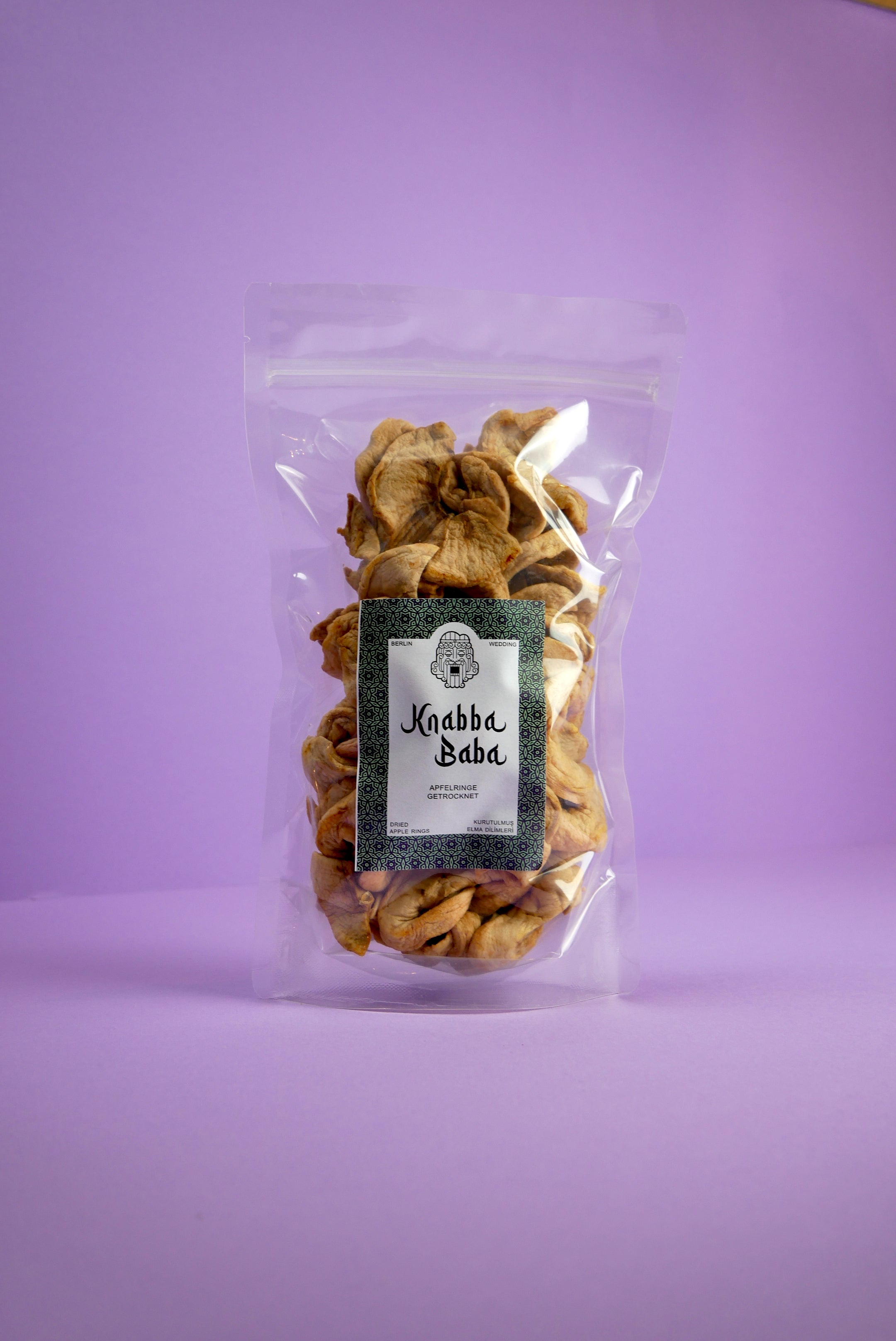 Knabba Baba Getrocknete Apfelringe 500 g in wiederverschließbarer Verpackung vor gelbem Hintergrund