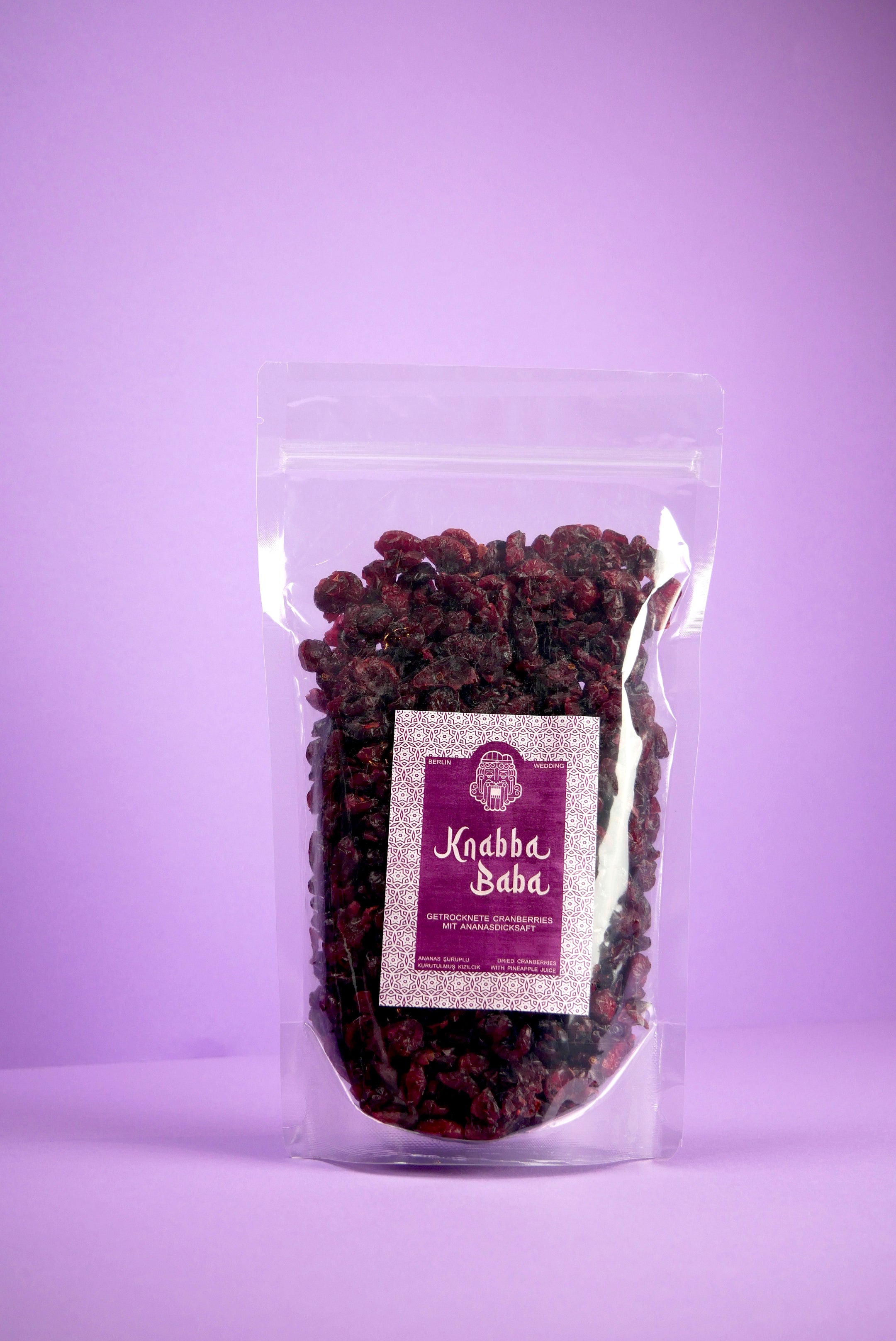 Knabba Baba Cranberries in transparentem wiederverschließbarem 500 g Beutel vor lila Hintergrund