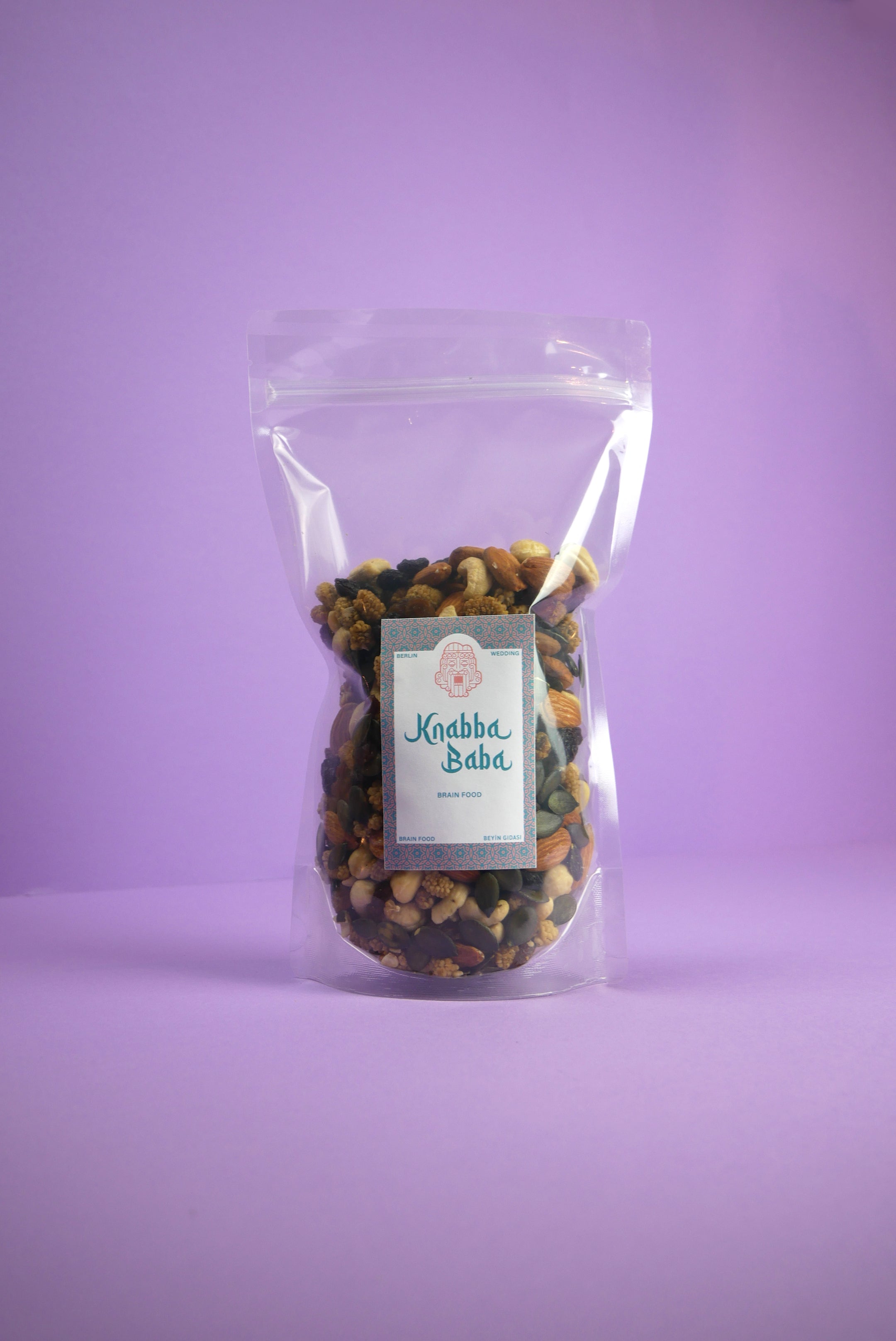 Knabba Baba Nussmischung Brain Food 500 g in wiederverschließbarer klarer Verpackung vor lilanem Hintergrund