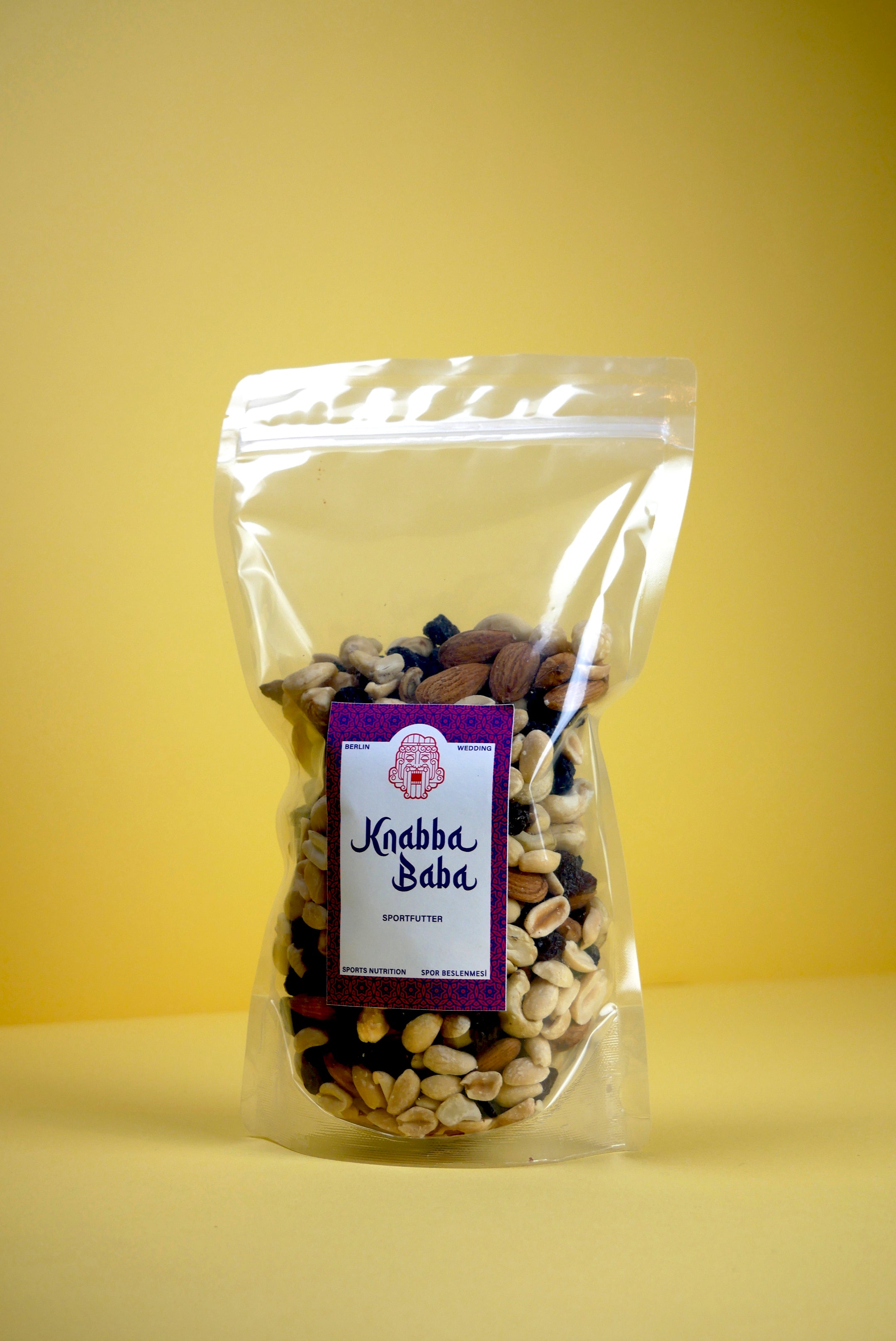 Knabba Baba Nussmischung in wiederverschließbarer klarer 500 g Verpackung vor gelbem Hintergrund
