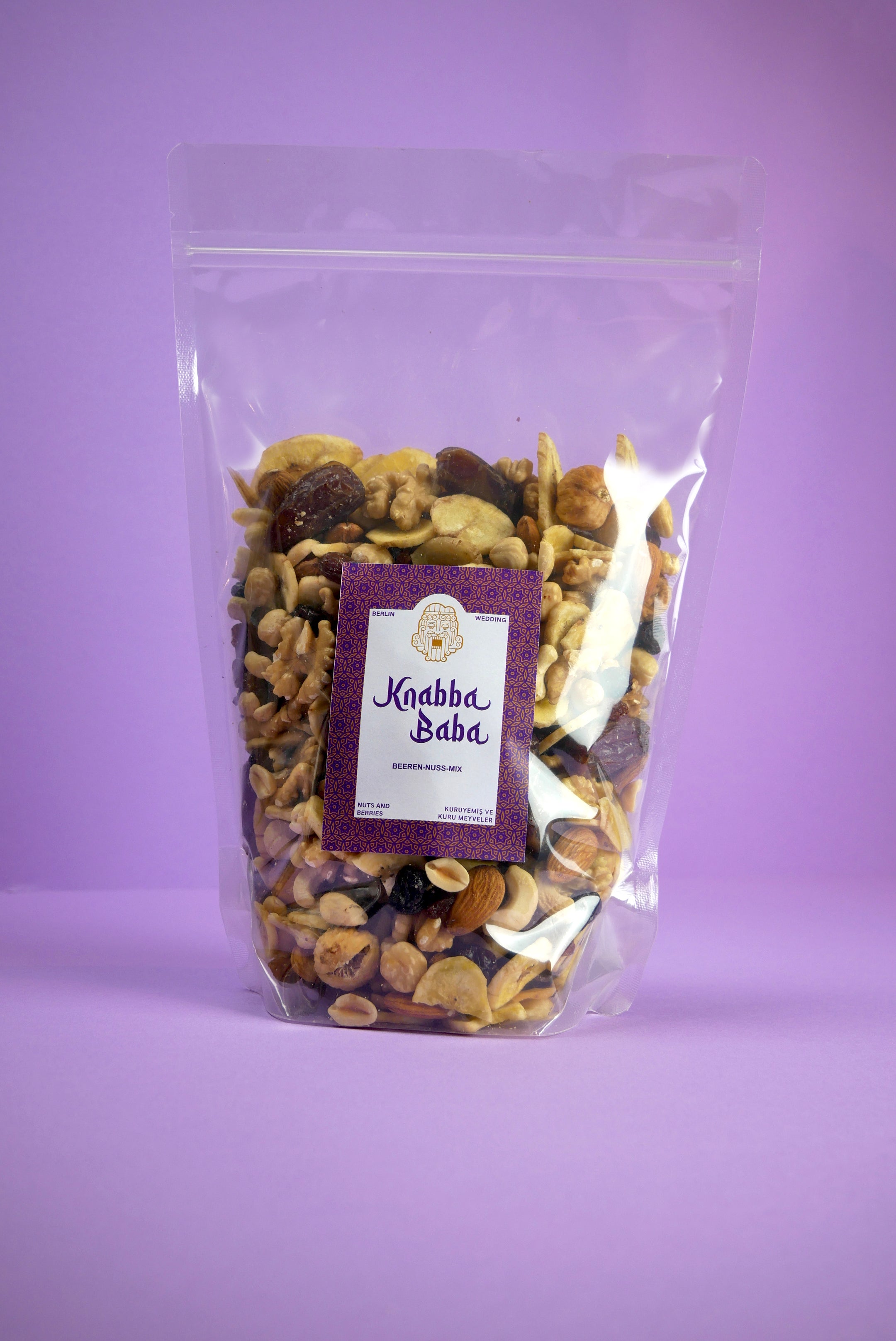 Knabba Baba Nussmischungen mit Beeren 1 kg in transparenter wiederverschließbarer Verpackung auf lila Hintergrund