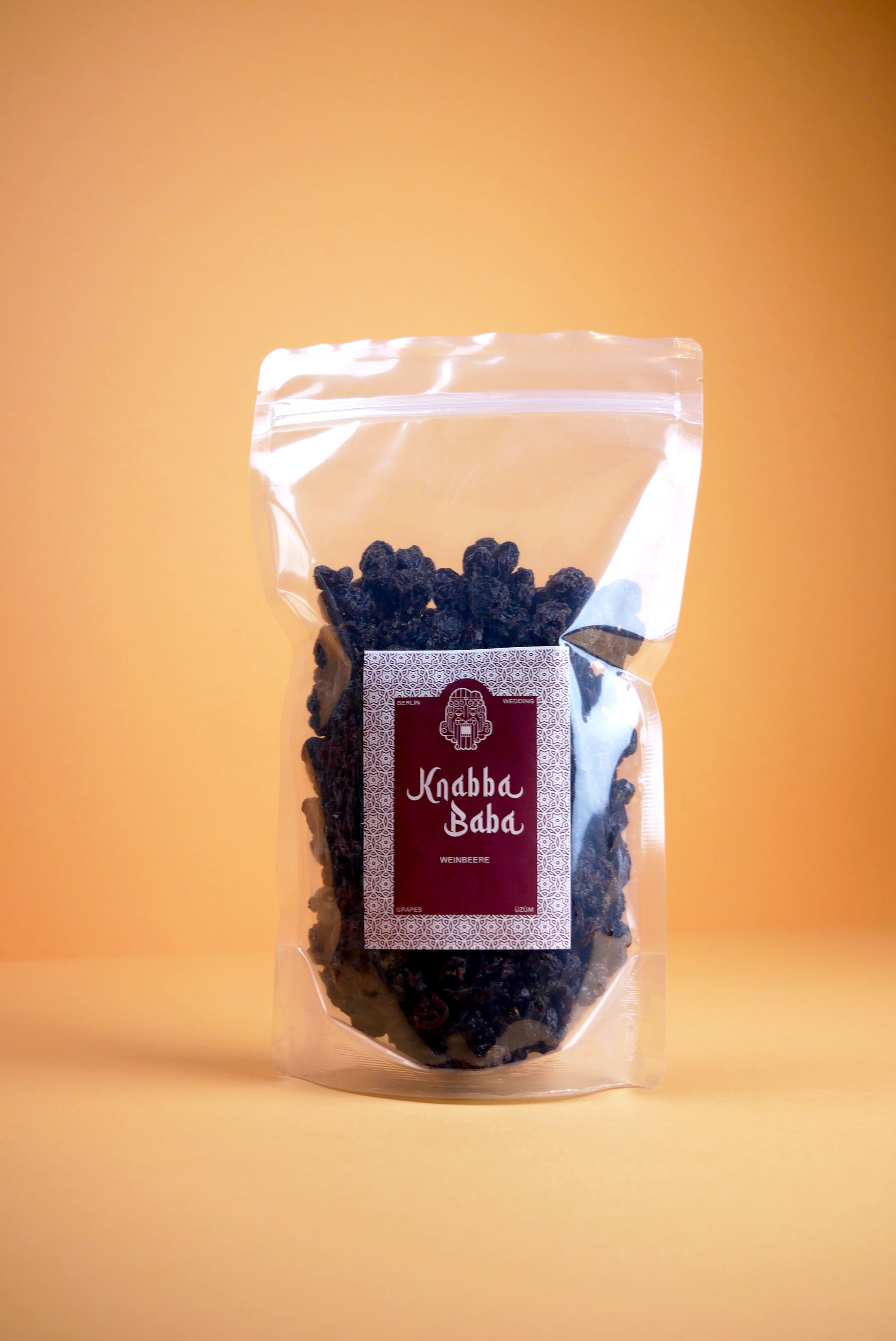 Knabba Baba Weinbeeren (Rosinen) 500 g in wiederverschließbarer Verpackung vor orangem Hintergrund