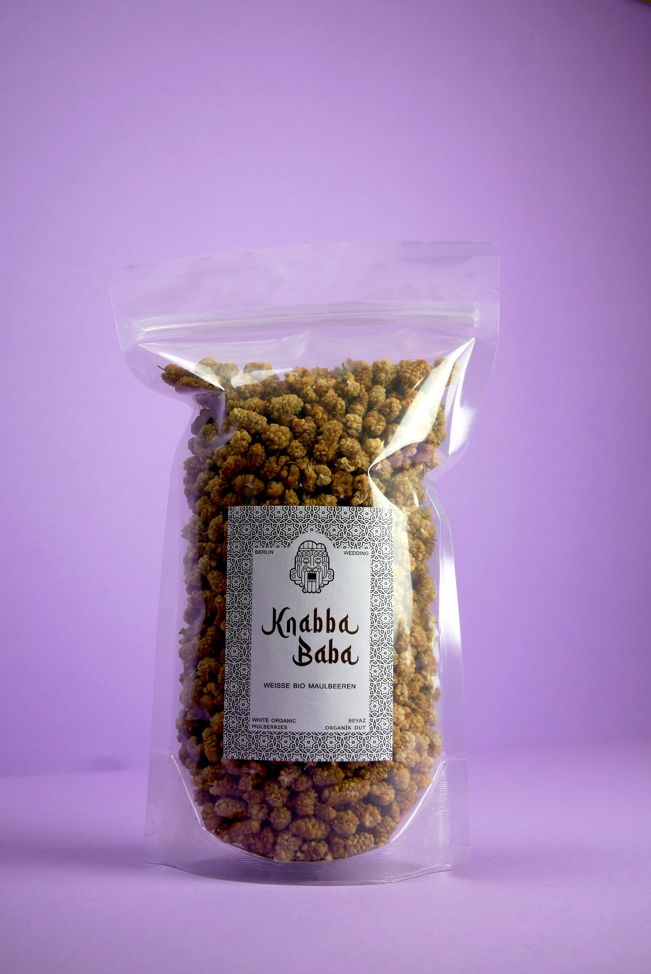 Knabba Baba  -weiße Bio Maulbeeren 500 g in wiederverschließbarer Verpackung vor lila Hintergrund